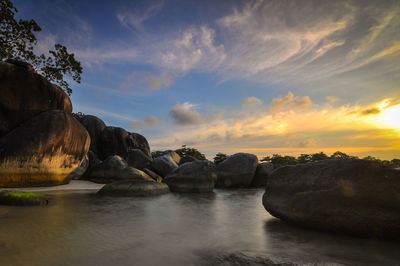 Rocks by sea against sky during sunset