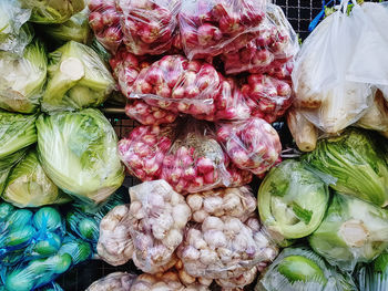 Various kinds of vegetables in plastic bags for sale at market stall