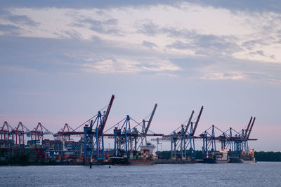 Cranes at commercial dock against sky