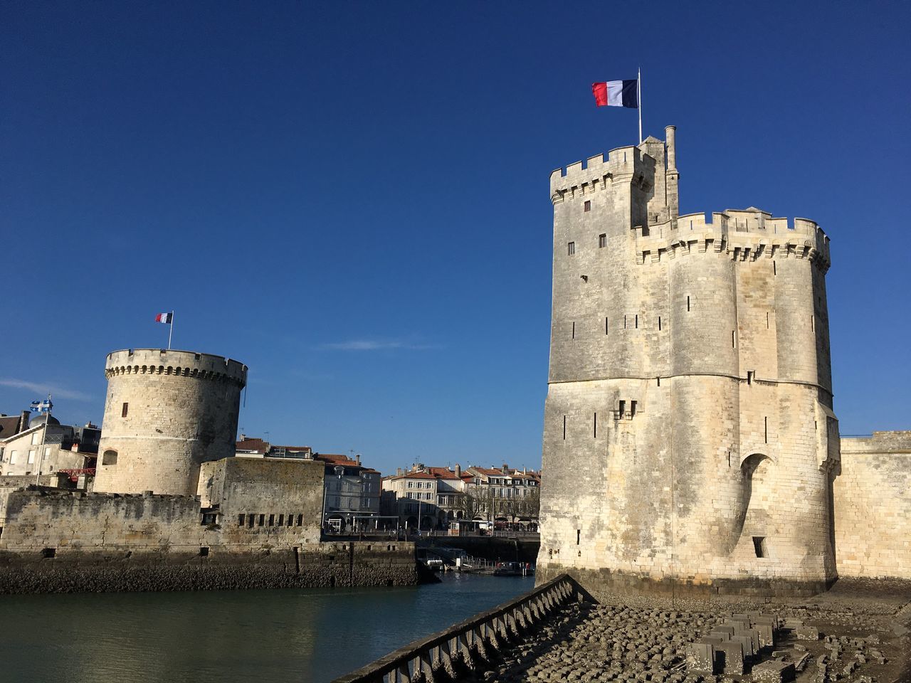 architecture, flag, tower, built structure, building exterior, clock tower, clear sky, patriotism, no people, outdoors, day, water, clock