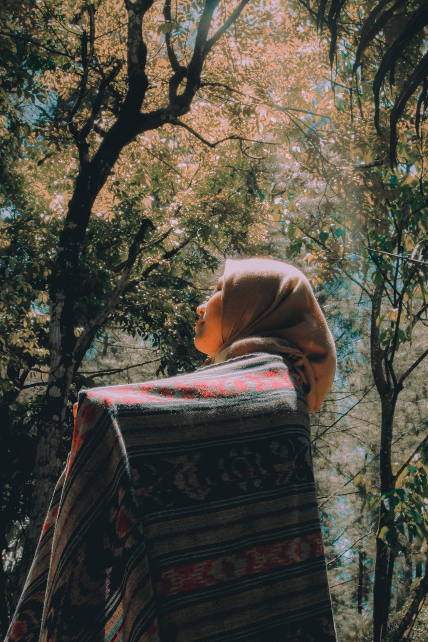 WOMAN RELAXING ON TREE TRUNK