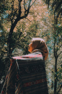 Woman relaxing on tree trunk in forest