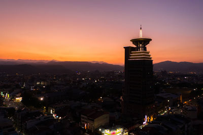 Illuminated buildings in city against sky during sunset