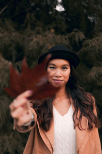 Portrait of young woman holding dry maple leaf