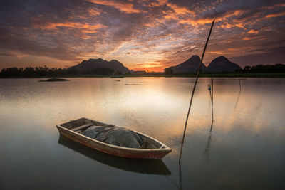 Boat moored on sea against sky during sunset