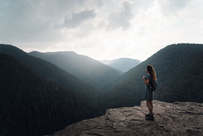 Rear view of man standing on mountain against sky