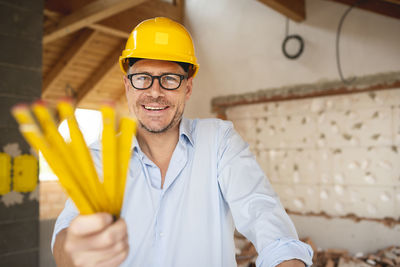 Portrait of smiling man standing against yellow wall