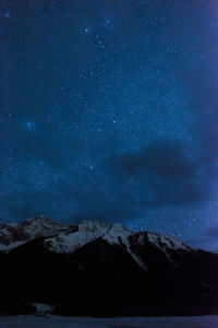 Scenic view of snowcapped mountains against sky at night