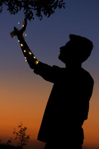 Low angle view of silhouette man standing against sky during sunset