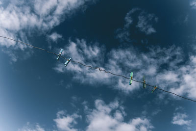 Low angle view of silhouette birds perching on rope against sky