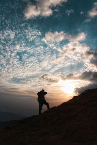 Silhouette man standing on mountain against sky during sunset