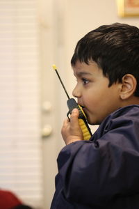 Side view of boy using walkie-talkie while playing at home