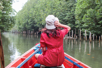 Rear view of woman with hat on lake against trees