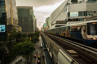 Train on railroad tracks amidst buildings in city against sky