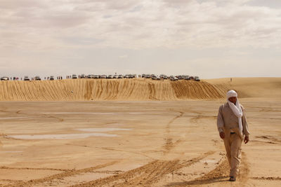 Man walking at desert against sky