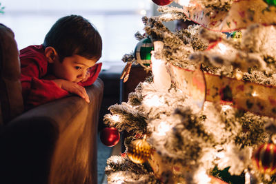 Young boy admiring christmas lights and decorations on a tree