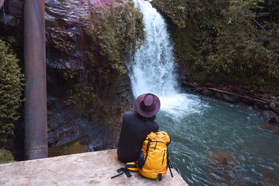 Man with yellow bag enjoying waterfall