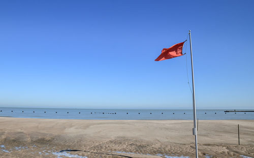 Flag on beach against clear sky