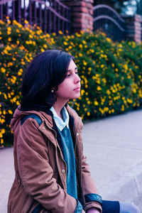 Thoughtful young woman looking away while relaxing at park