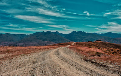 Scenic view of road by mountains against sky