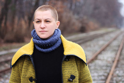 Woman looking away standing on railroad track during winter