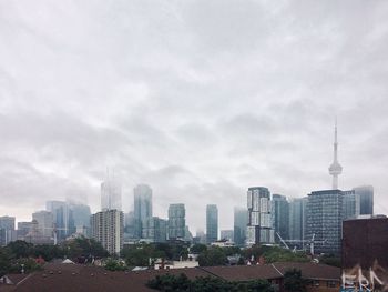 Buildings in city against cloudy sky