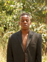 Portrait of young man standing against plants