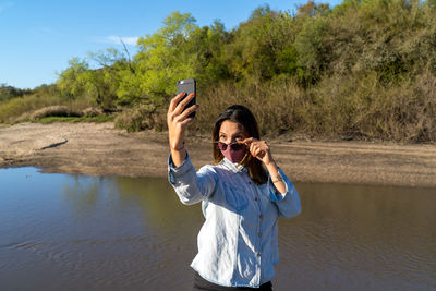 Full length of woman photographing on mobile phone