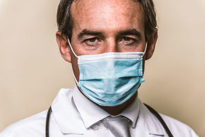 Portrait of smiling doctor wearing mask against colored background