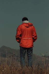 Rear view of man standing on field against sky