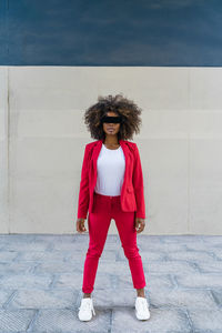 Mid adult woman with blindfold standing against wall