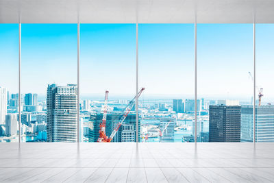 Modern buildings in city against sky seen through glass window