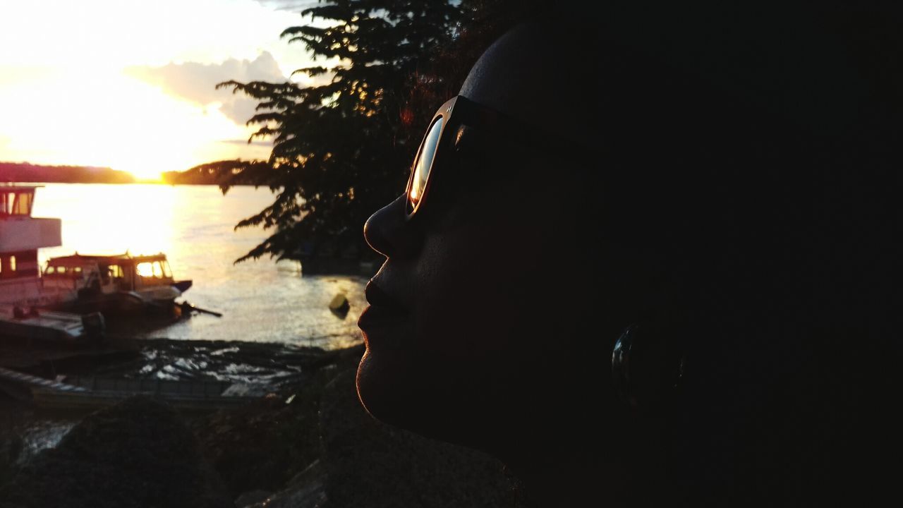 real people, one person, sunglasses, side view, sunset, sea, leisure activity, headshot, outdoors, silhouette, lifestyles, water, beach, boys, vacations, men, sky, close-up, childhood, food, tree, nature, day, people