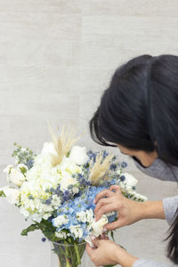 Close-up of woman arranging flowers in vase