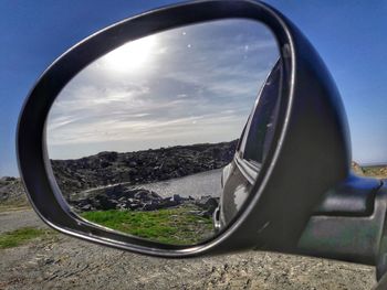 Reflection of sky on side-view mirror of car