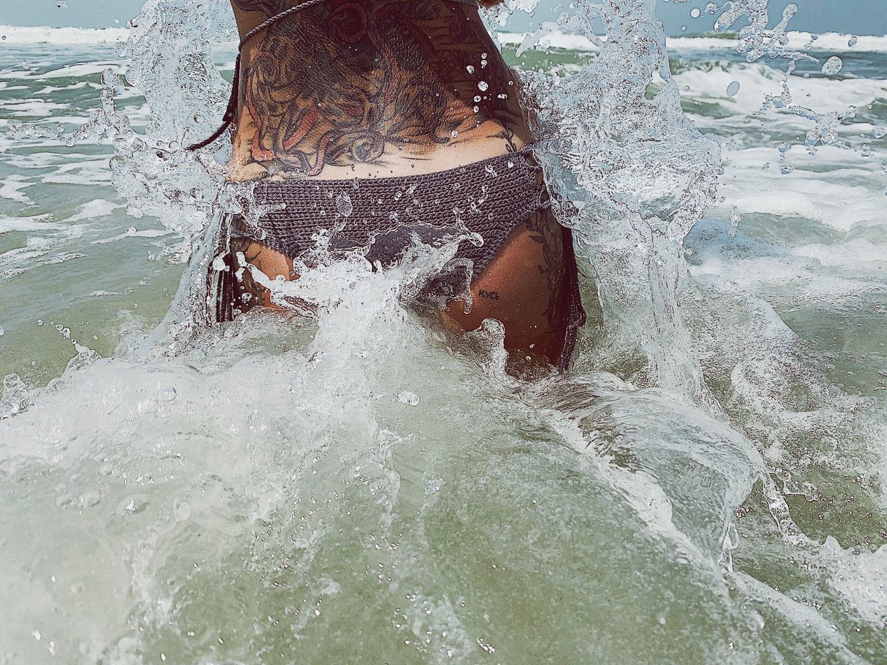 LOW SECTION OF WOMAN SPLASHING ON SWIMMING POOL