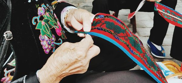 Midsection of man and holding sewing colorful textile