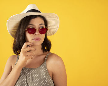 Portrait of young woman wearing sunglasses against gray background