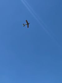 Low angle view of airplane against clear blue sky