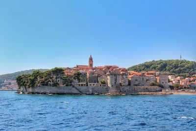 Scenic view of sea and buildings against clear blue sky