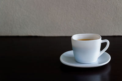 Close-up of coffee cup on table against wall