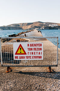 Information sign on beach against clear sky