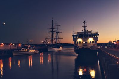 Boats moored at harbor at night