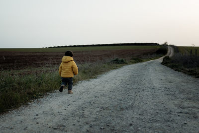 Rear view of man walking on road