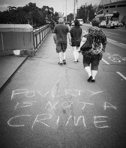 Rear view of people walking on road in city