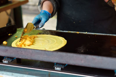 Midsection of person making dosa for sale at market