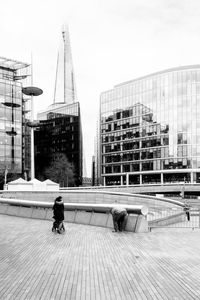 Man and woman on boardwalk against modern buildings