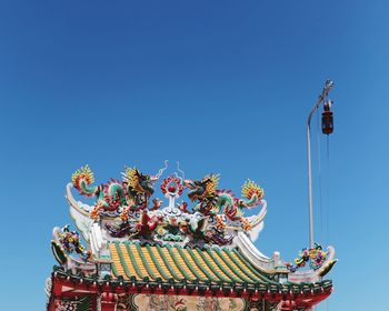 Low angle view of carousel against clear blue sky