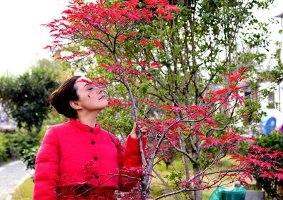 Woman smelling plant while standing at park