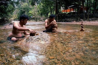 Friends playing with pebble in river